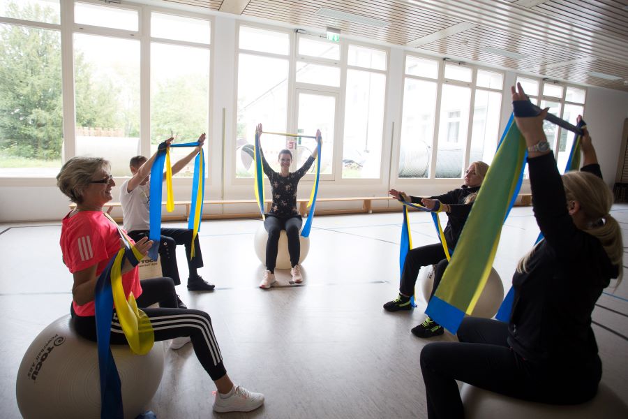 Personengruppe auf Pezzibällen sitzend mit Therapiebändern Personengruppe auf Pezzibällen sitzend mit Therapiebändern
